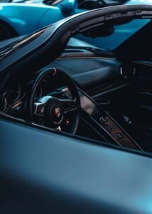 Sports car interior with focus on steering wheel logo, control buttons, and visible dashboard.