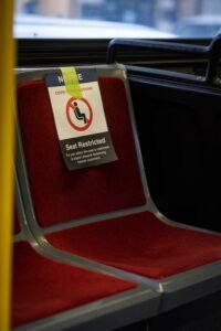 Bus seat with red cushion marked restricted for COVID-19 distancing precautions.