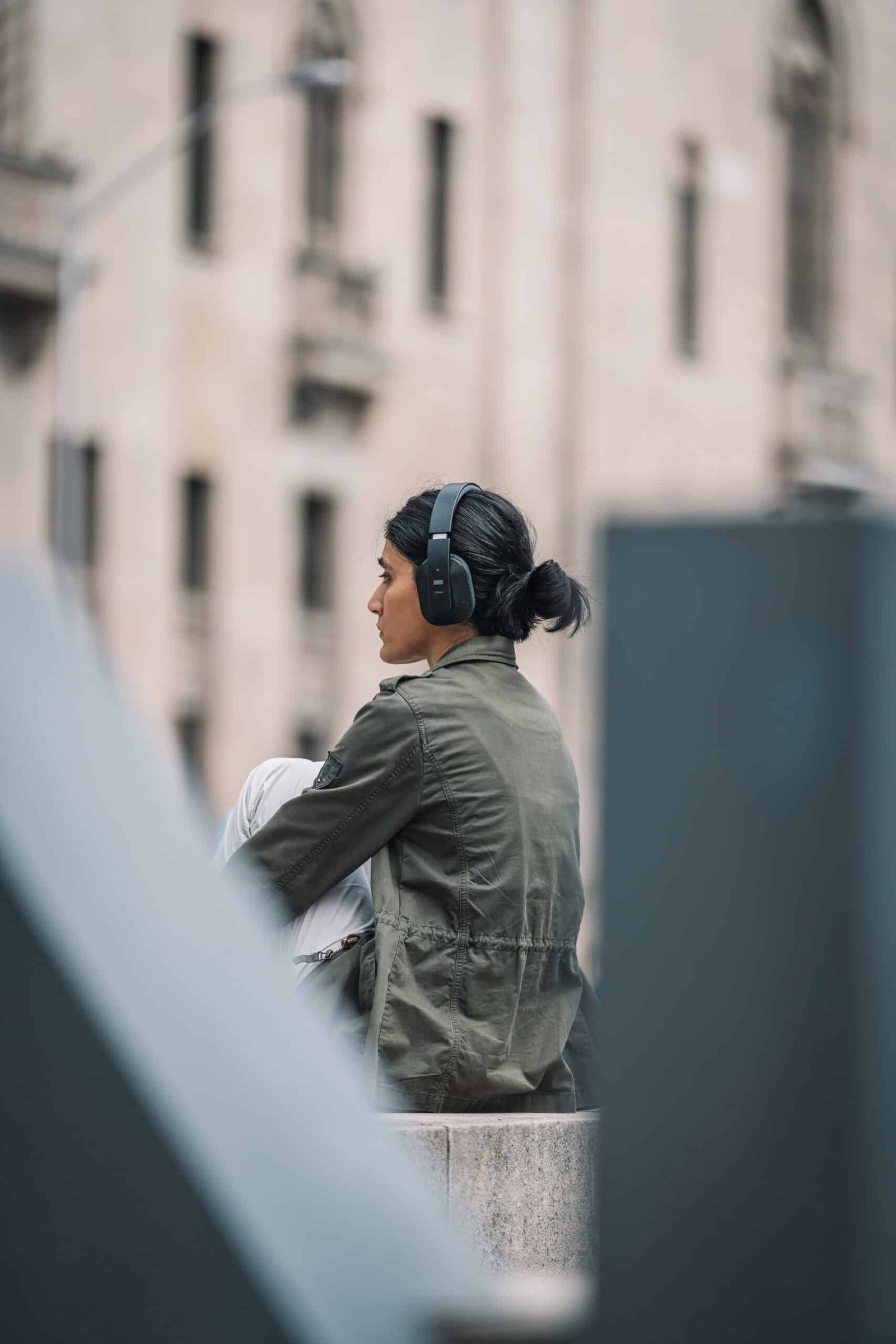 An image of a girl wearing headphones, sitting on a ledge in front of Union Station