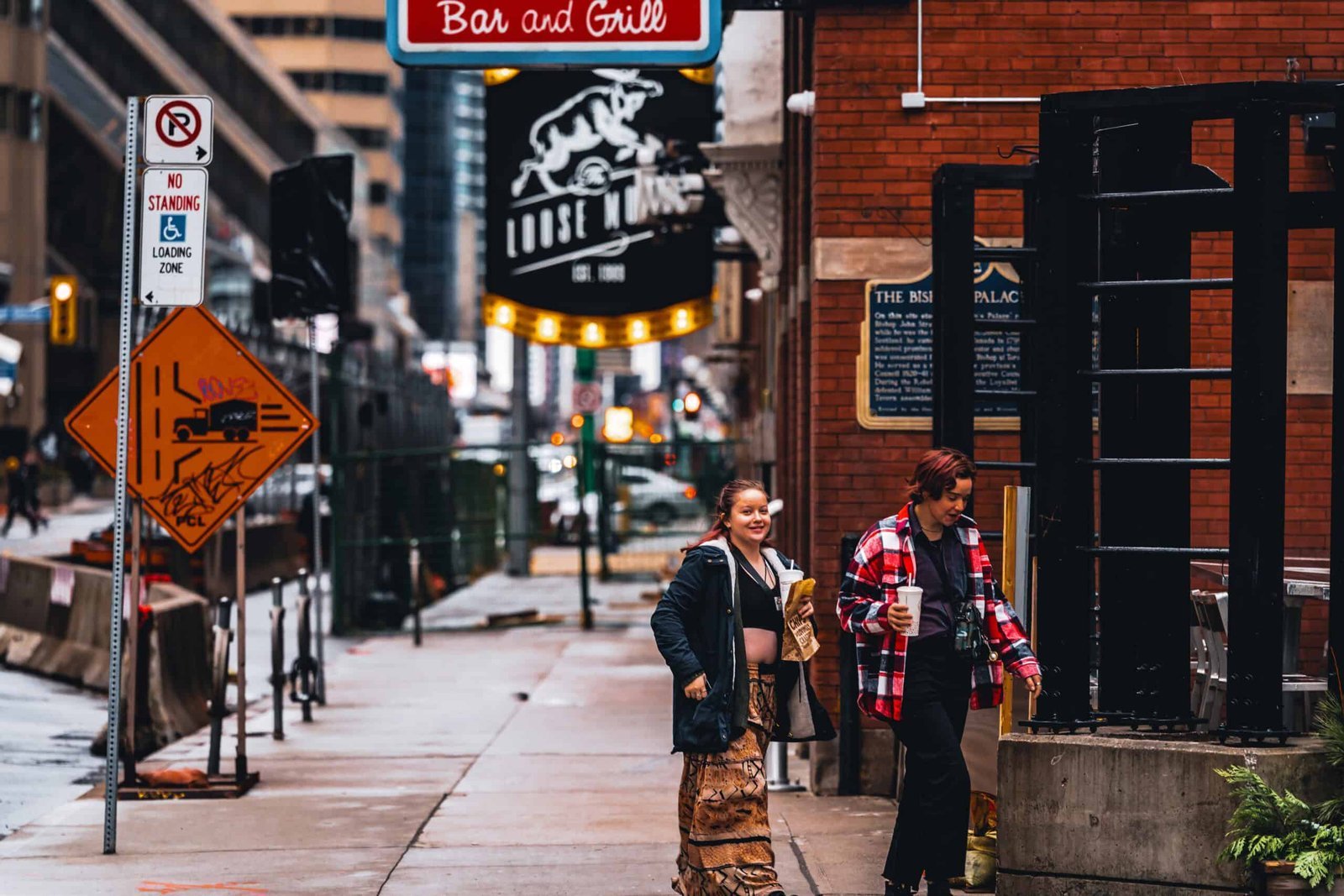 An image of 2 girls crossing the street laughing and looking at the camera